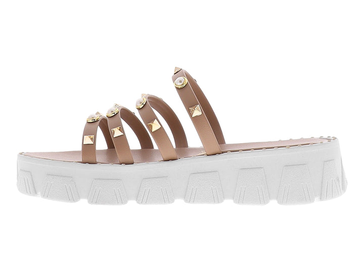 Sandalias de plataforma color maquillaje con tiras adornadas con perlas y tachuelas doradas sobre suela blanca.