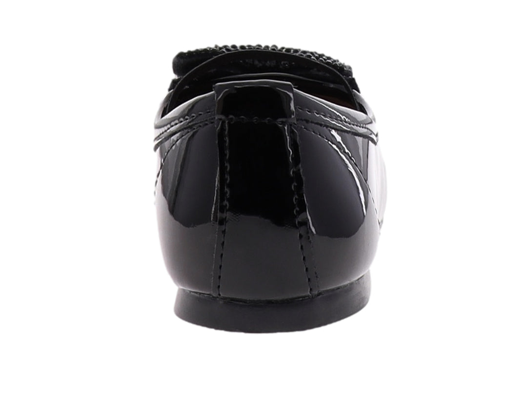 Zapato plano de charol negro para niña con correa y moño decorativo en la punta.