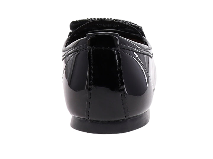 Zapato plano de charol negro para niña con correa y moño decorativo en la punta.