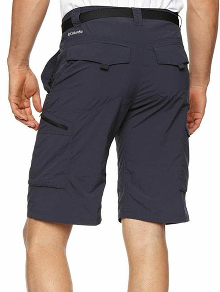Hombre vistiendo shorts cargo Columbia color azul marino con cinturón negro y tenis blancos.
