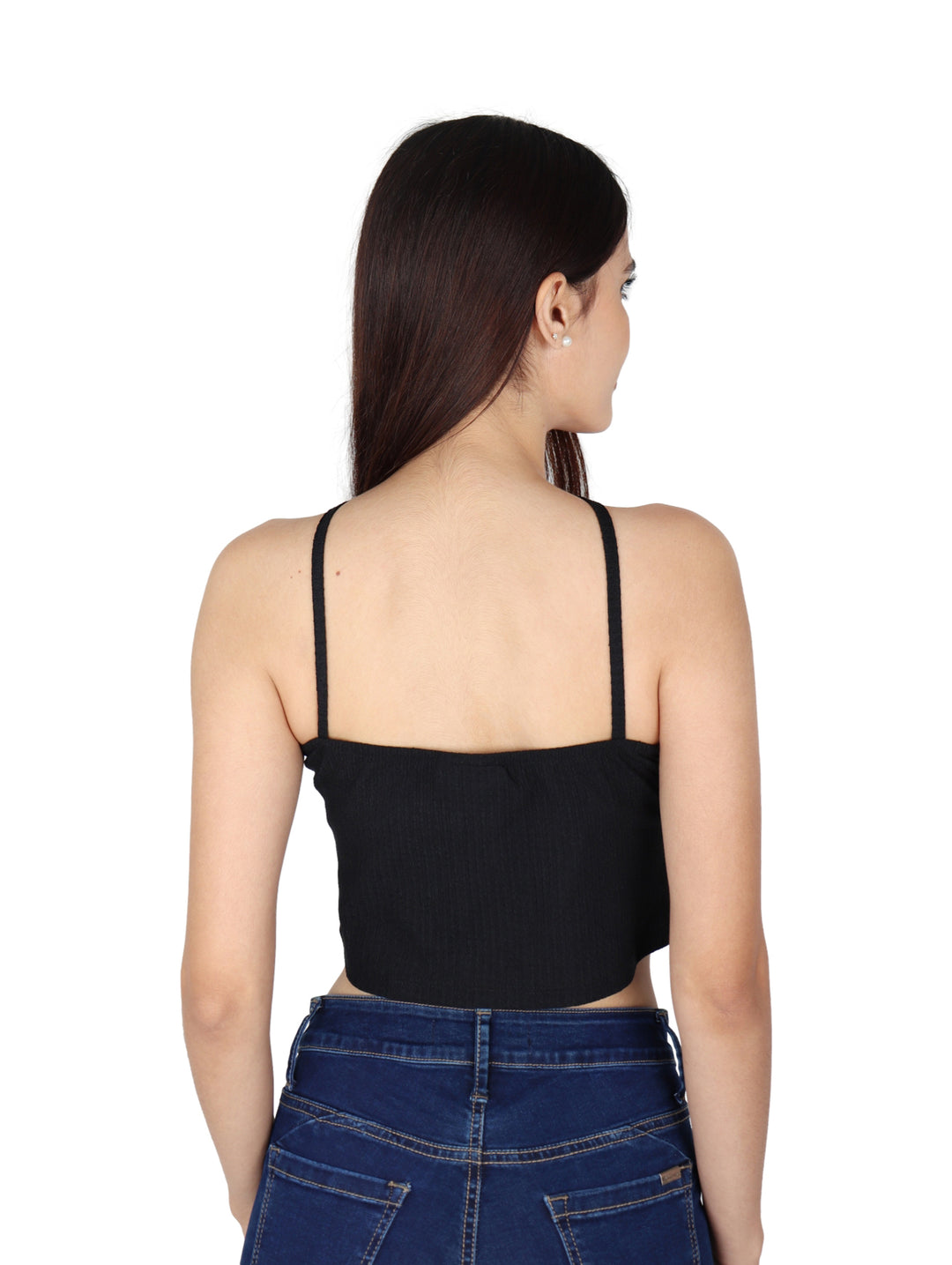 Mujer vistiendo un crop top negro de cuello halter y jeans azules sobre fondo blanco.
