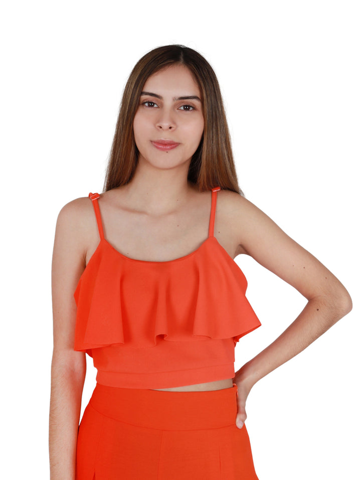 Mujer vistiendo blusa corta color naranja con tirantes y detalle de volante frontal.