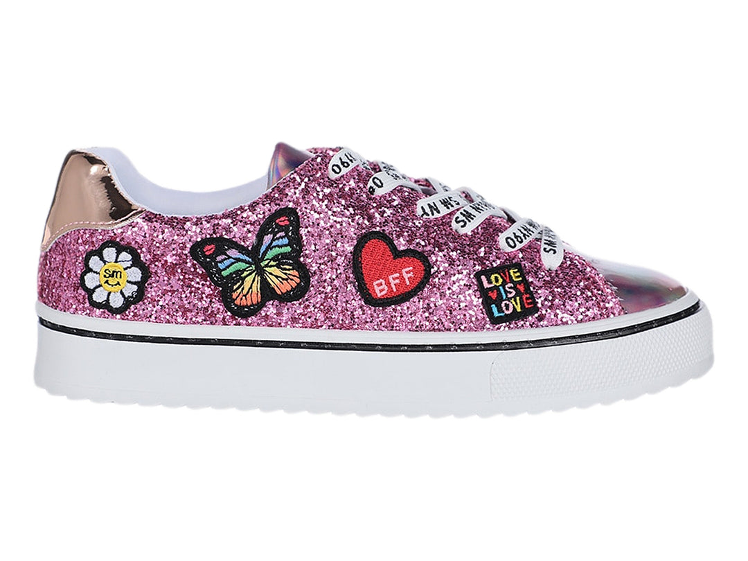 Tenis infantiles rosa con glitter, adornos de mariposa y corazón, y punta holográfica.