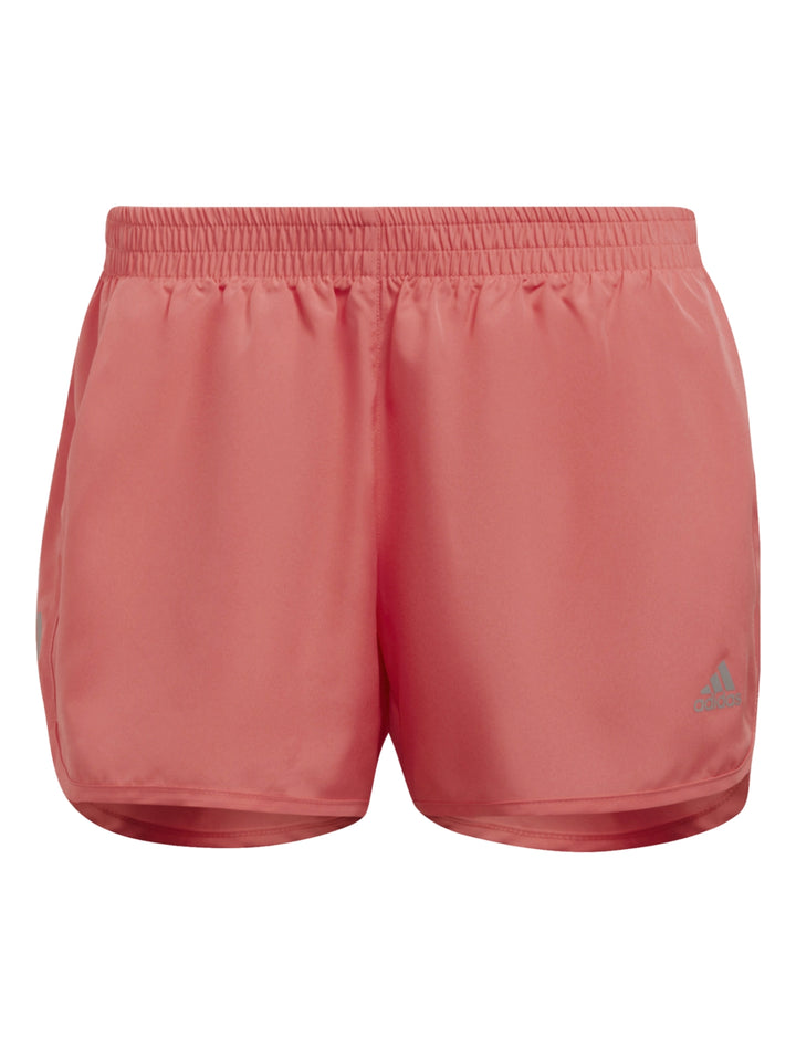 Mujer vistiendo shorts deportivos Adidas color coral para correr sobre fondo blanco.
