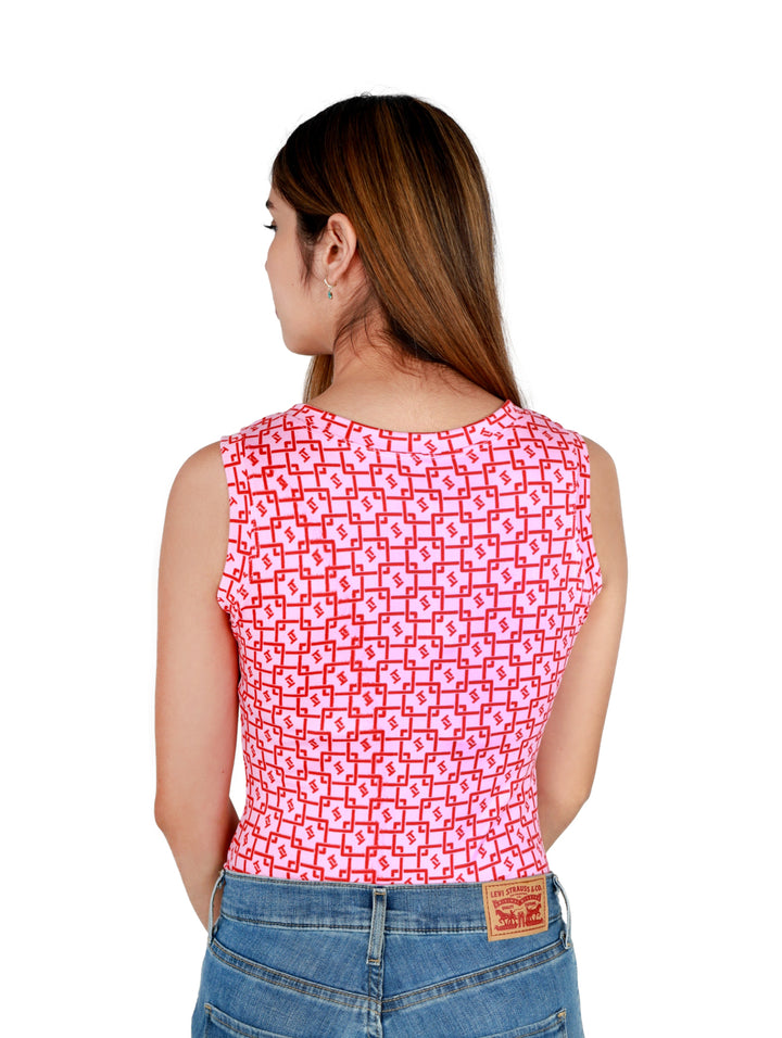 Mujer vistiendo una pantiblusa rosa con estampado geométrico rojo y pantalones de mezclilla azules.