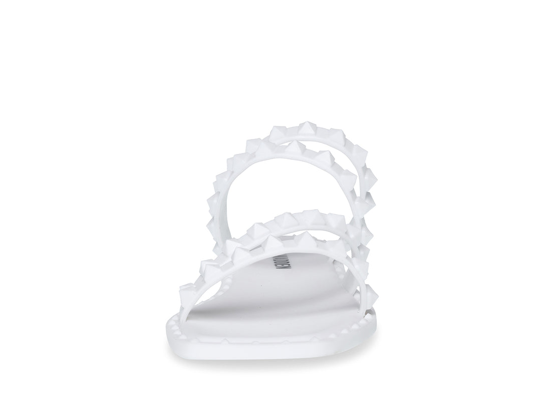 Sandalia blanca de Steve Madden con correas frontales decoradas con bordes dentados y suela plana.