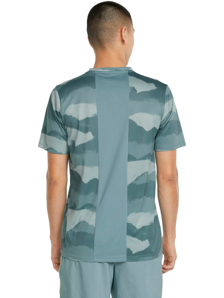 Hombre vistiendo camiseta deportiva PUMA color mineral blue con estampado abstracto en tonos azules y verdes.
