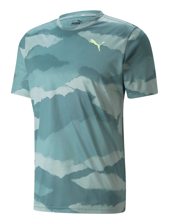 Hombre vistiendo camiseta deportiva PUMA color mineral blue con estampado abstracto en tonos azules y verdes.