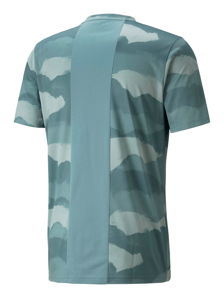 Hombre vistiendo camiseta deportiva PUMA color mineral blue con estampado abstracto en tonos azules y verdes.