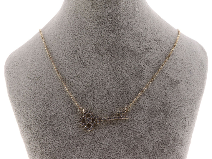 Collar dorado con cadena delgada y dije en forma de llave adornado con cristales oscuros.