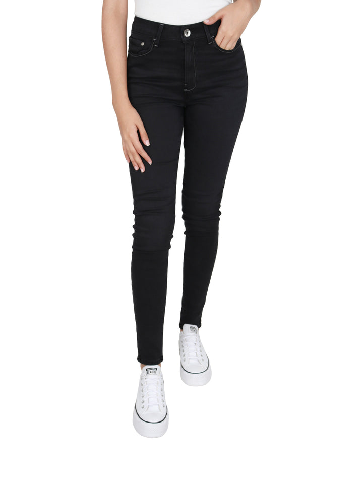 Mujer vistiendo pantalones OGGI Black Lucy Jeans ajustados en color negro y tenis blancos.