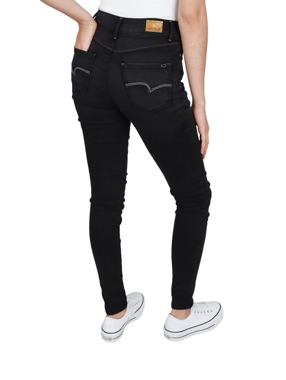 Mujer vistiendo pantalones OGGI Black Lucy Jeans ajustados en color negro y tenis blancos.