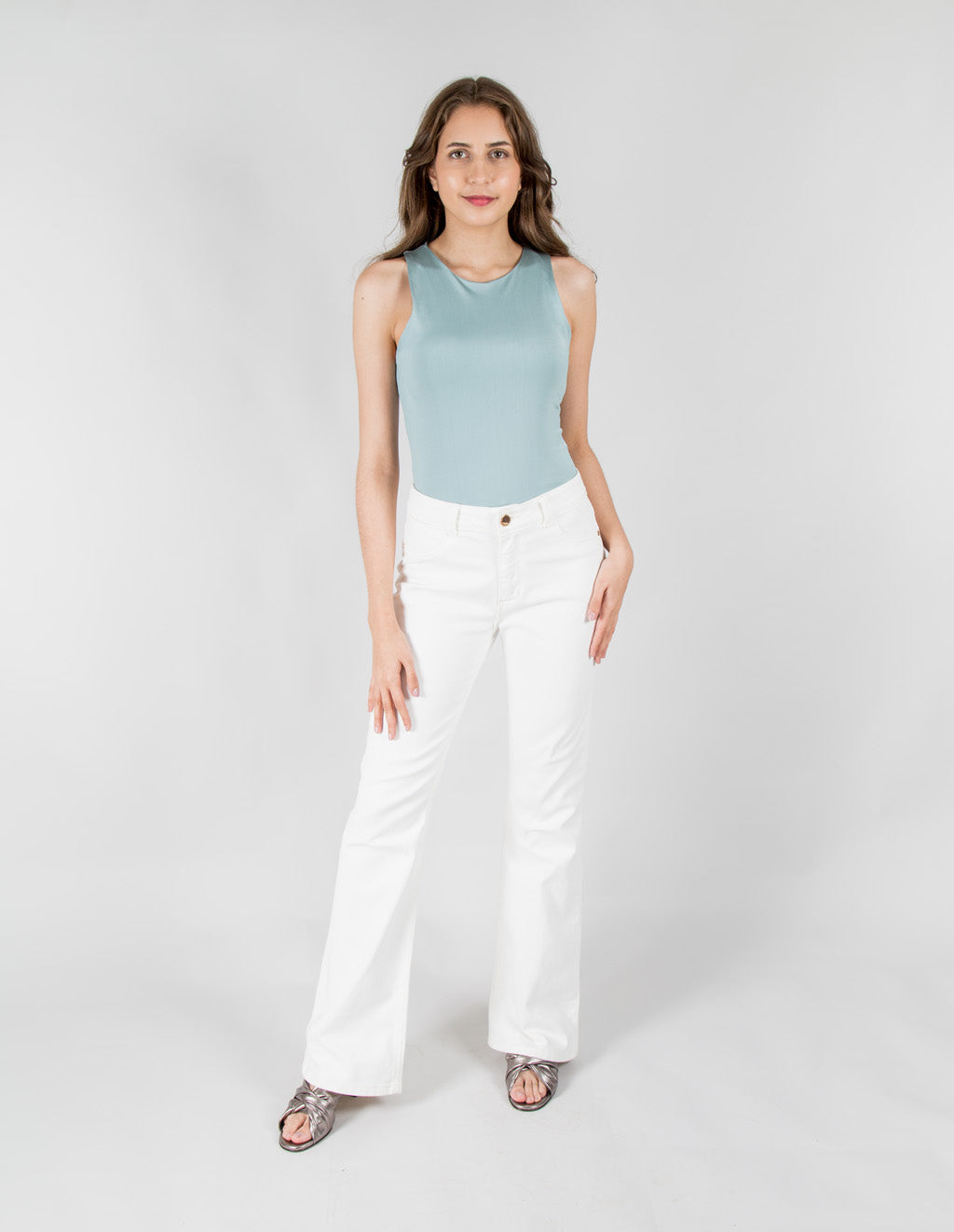 Mujer modelando pantalones jeans blancos de corte acampanado.