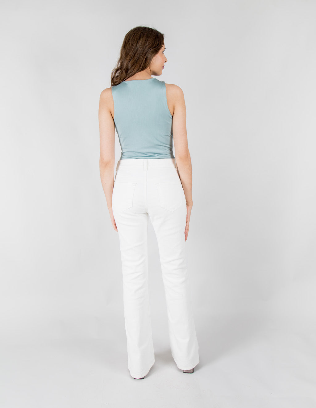 Mujer modelando pantalones jeans blancos de corte acampanado.