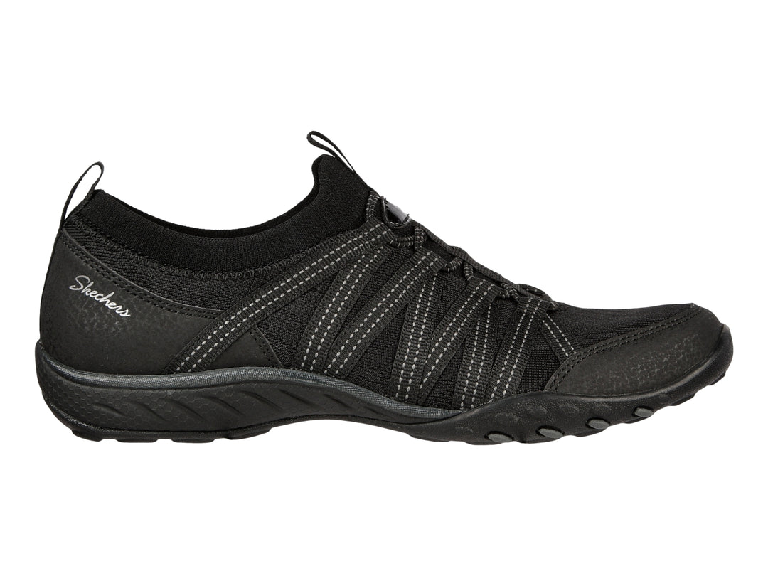 Tenis deportivos Skechers para mujer en color negro con detalles de costuras blancas y suela negra.
