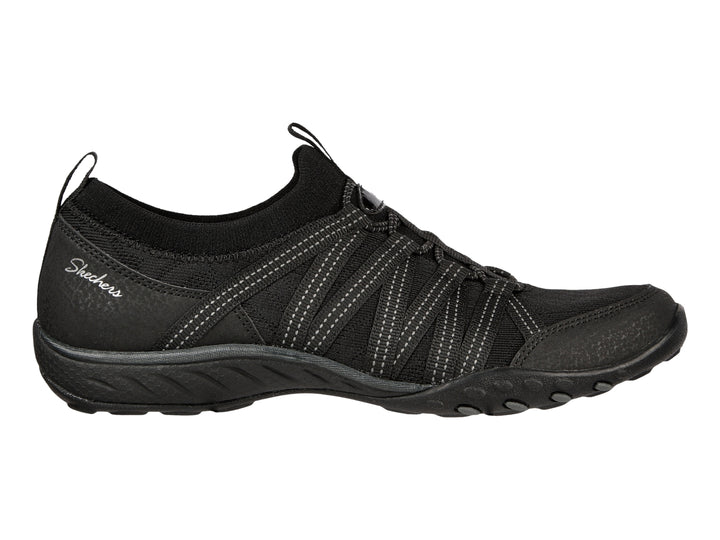 Tenis deportivos Skechers para mujer en color negro con detalles de costuras blancas y suela negra.