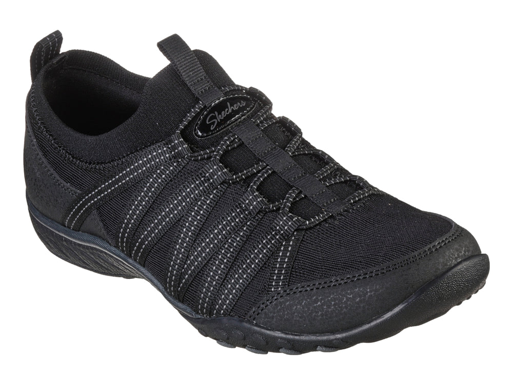 Tenis deportivos Skechers para mujer en color negro con detalles de costuras blancas y suela negra.
