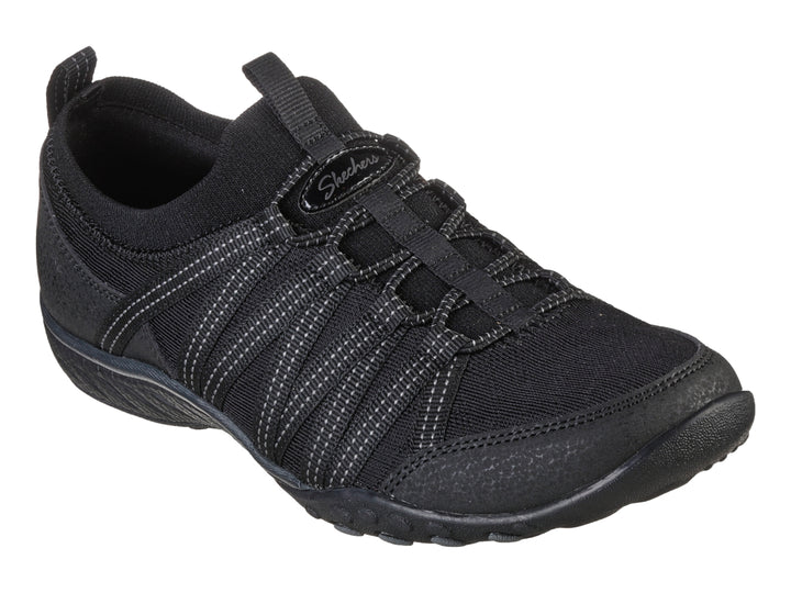 Tenis deportivos Skechers para mujer en color negro con detalles de costuras blancas y suela negra.