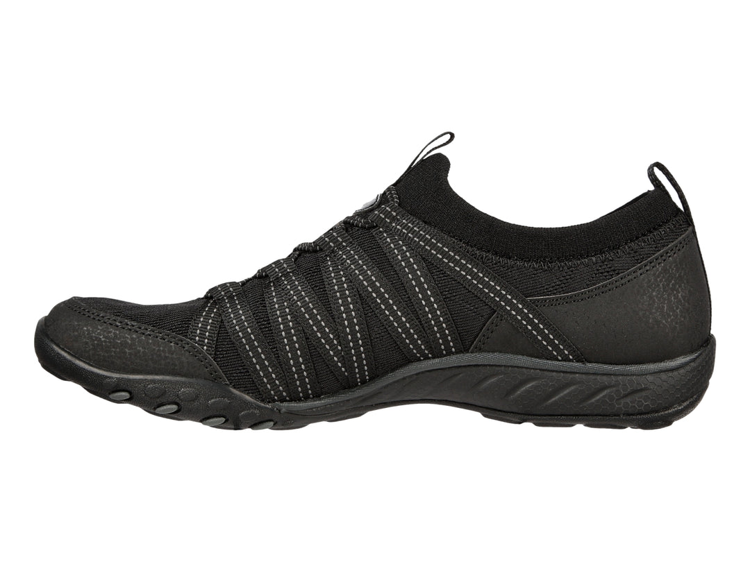Tenis deportivos Skechers para mujer en color negro con detalles de costuras blancas y suela negra.
