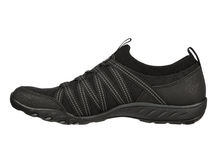 Tenis deportivos Skechers para mujer en color negro con detalles de costuras blancas y suela negra.