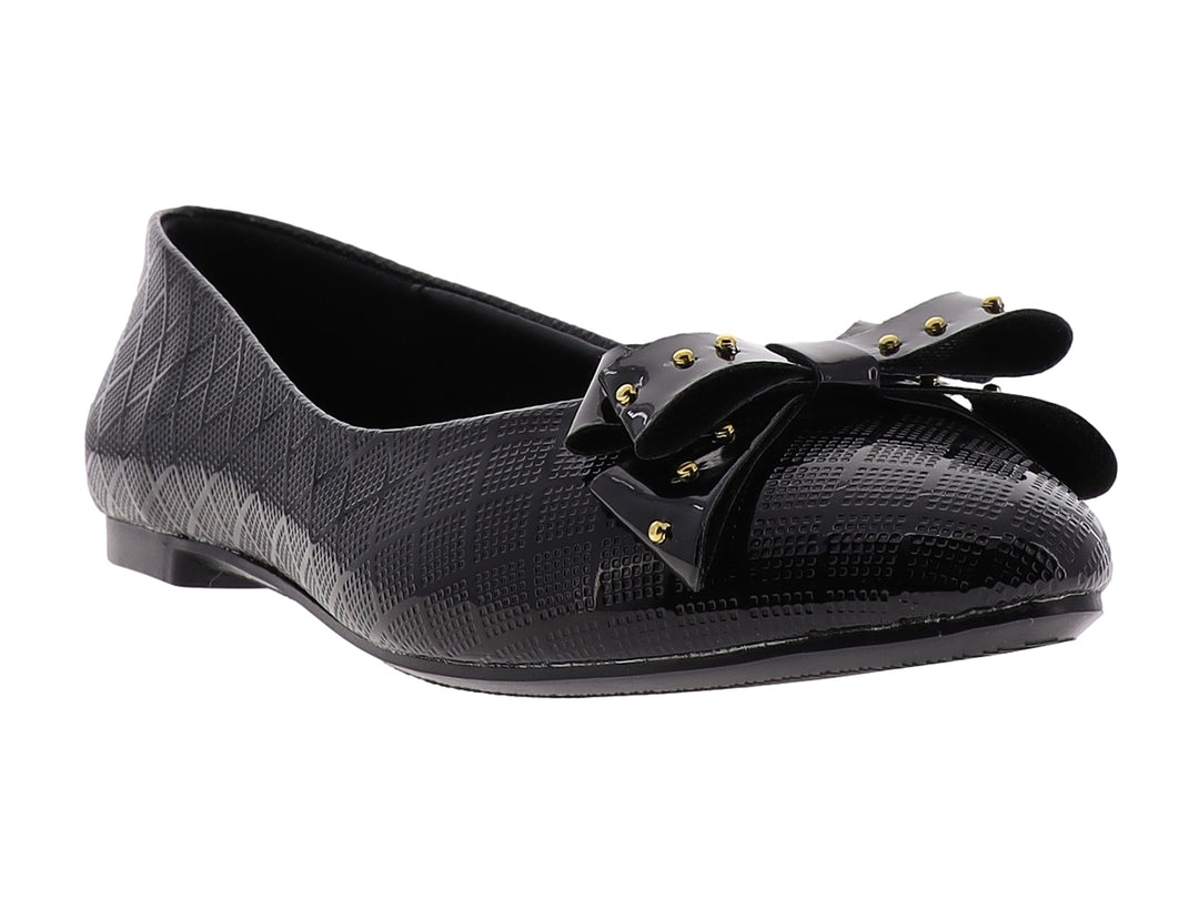 Zapato plano negro brillante para niña con moño decorado con tachuelas doradas.