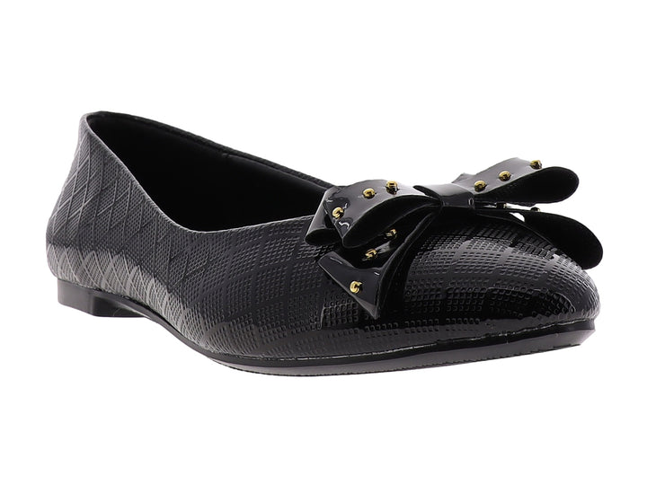 Zapato plano negro brillante para niña con moño decorado con tachuelas doradas.