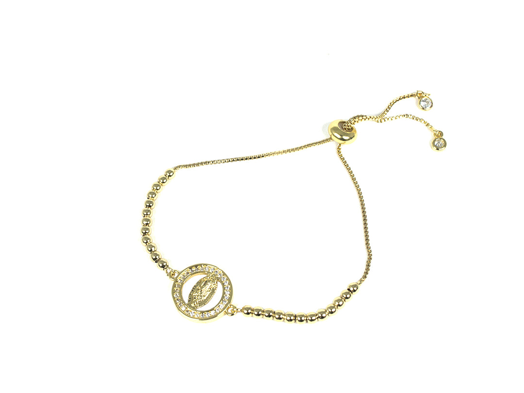 Pulsera dorada con dije circular central y cierre ajustable con cuentas pequeñas.