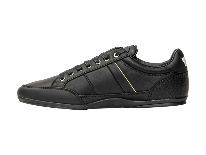 Tenis Lacoste color negro para hombre con franja blanca lateral y logotipo dorado.