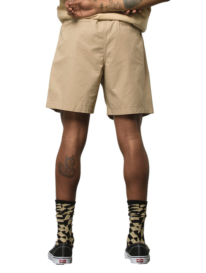 Hombre vistiendo pantalones cortos VANS color khaki con cintura elástica y cordón.