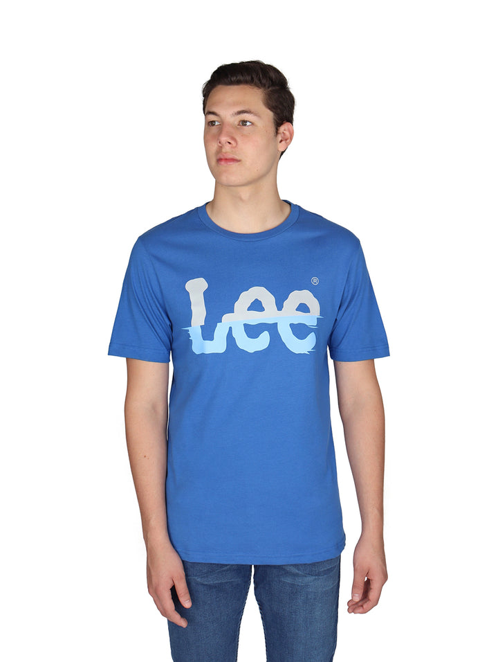 Hombre vistiendo playera azul de manga corta con logotipo de Lee estampado en el pecho.