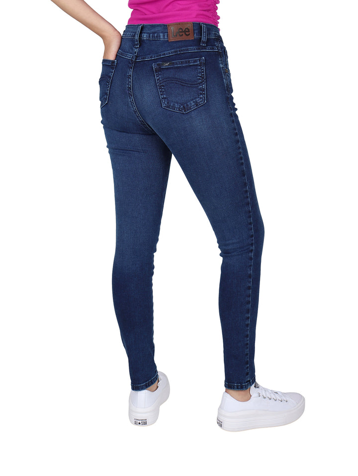 Mujer vistiendo pantalones LEE skinny jeans de color índigo, cintura alta y tenis blancos.