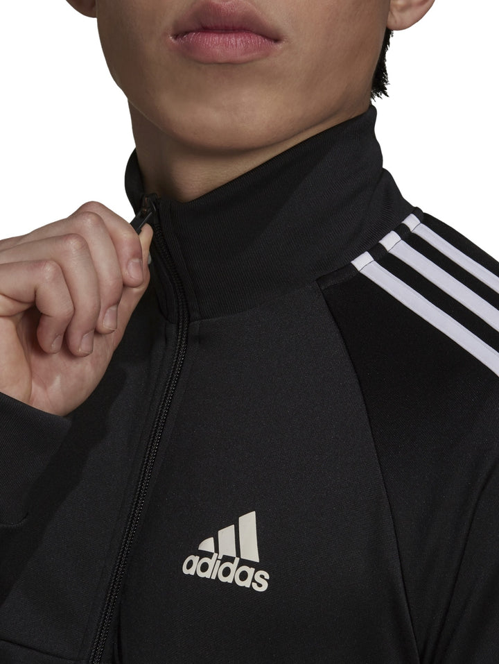 Hombre vistiendo chaqueta deportiva Adidas Aeroready Sereno Cut color negro con rayas blancas laterales.