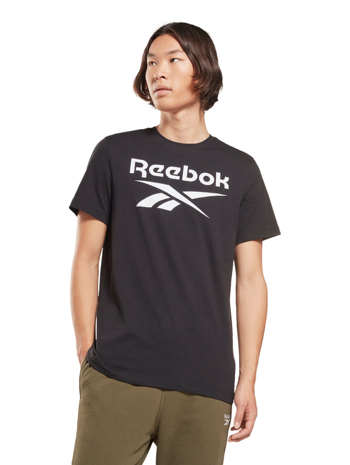 Hombre usando playera negra de manga corta con logotipo blanco de Reebok en el pecho.