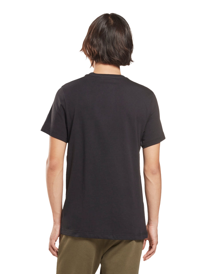Hombre usando playera negra de manga corta con logotipo blanco de Reebok en el pecho.