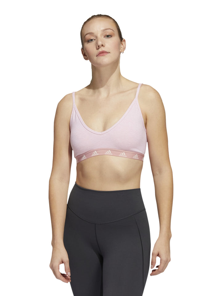 Bra deportivo Adidas en color rosa claro con tirantes delgados y banda elástica inferior blanca.