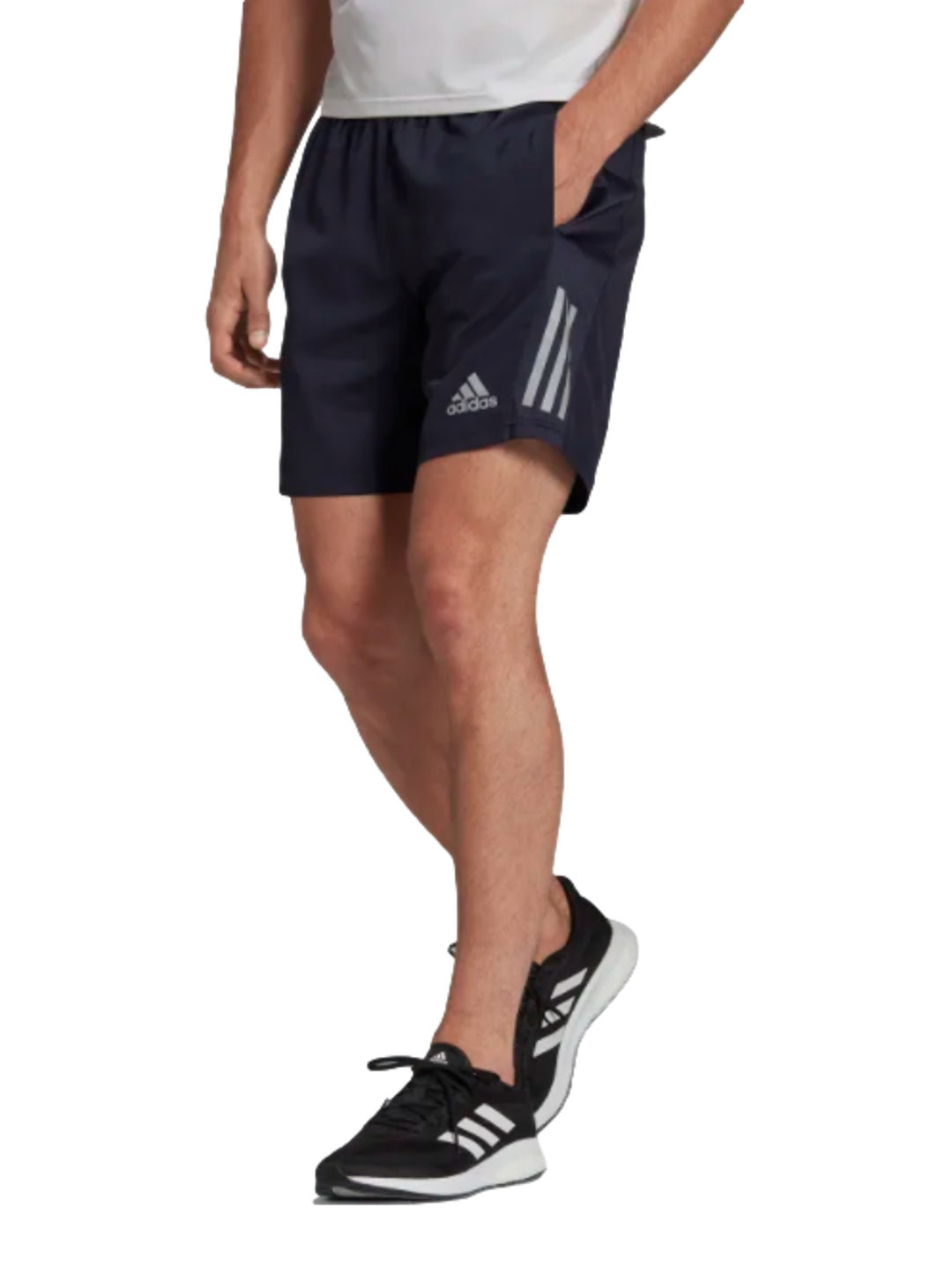 Hombre vistiendo shorts deportivos Adidas color azul marino Legend Ink con detalles laterales reflectantes.