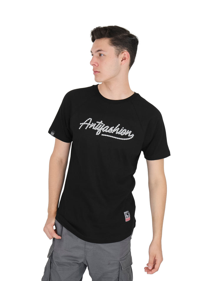 Hombre vistiendo playera negra de manga corta con la palabra Antifashion en letras blancas cursivas al frente.
