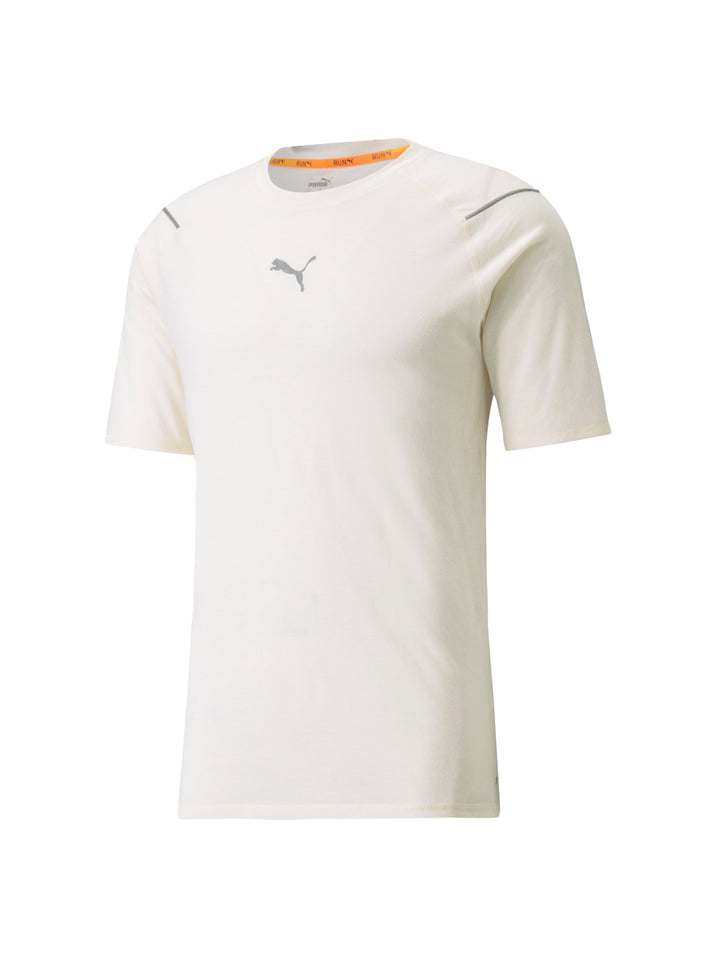 Hombre vistiendo camiseta deportiva PUMA de color marfil y shorts grises sobre fondo blanco.