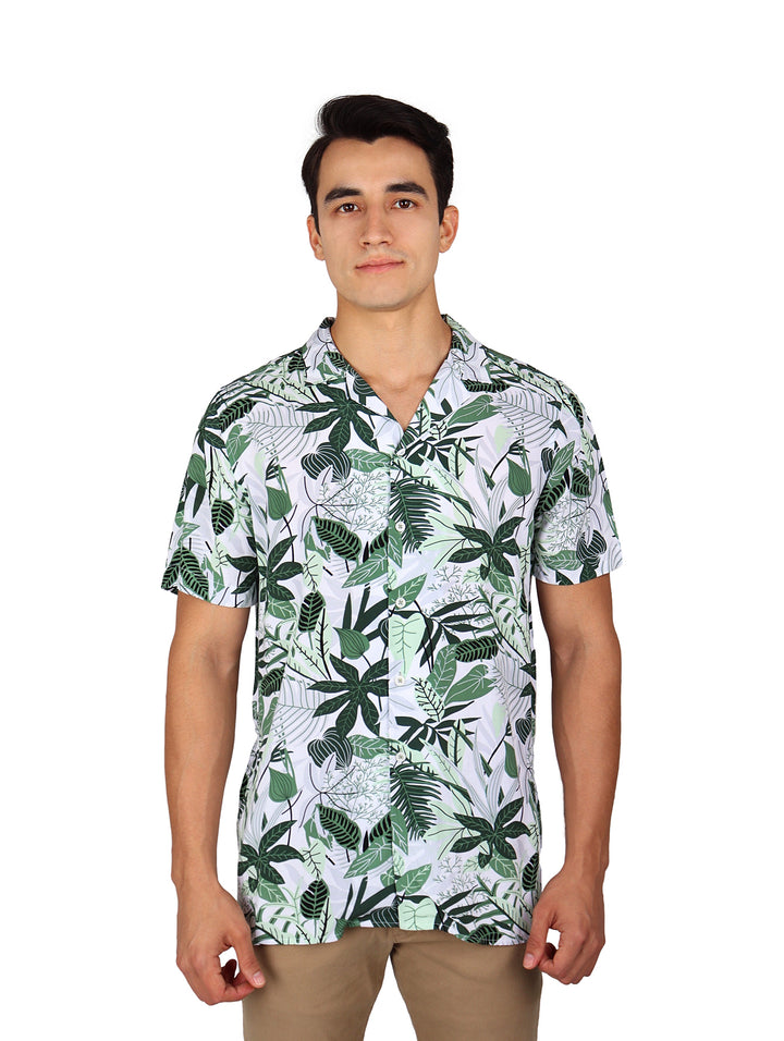 Hombre vistiendo camisa de manga corta blanca con estampado de hojas tropicales verdes.