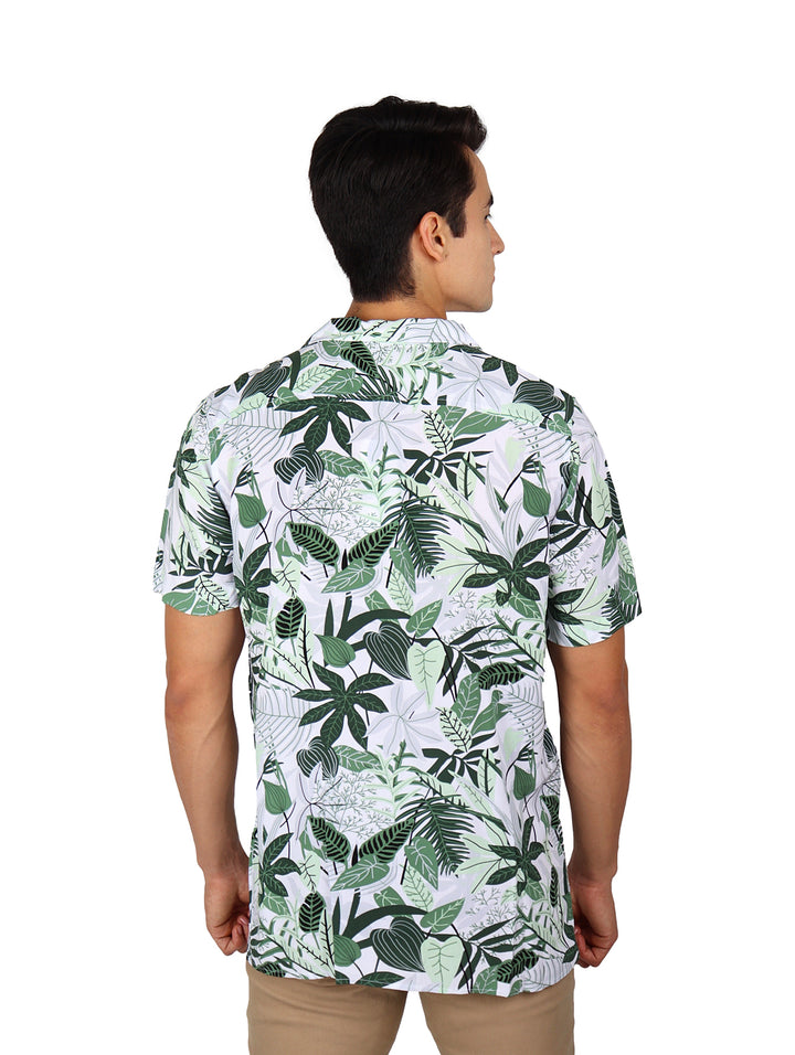 Hombre vistiendo camisa de manga corta blanca con estampado de hojas tropicales verdes.