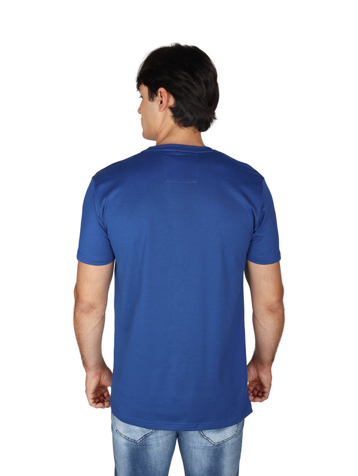 Hombre vistiendo playera azul royal de manga corta con estampado circular en el pecho y cuello redondo.
