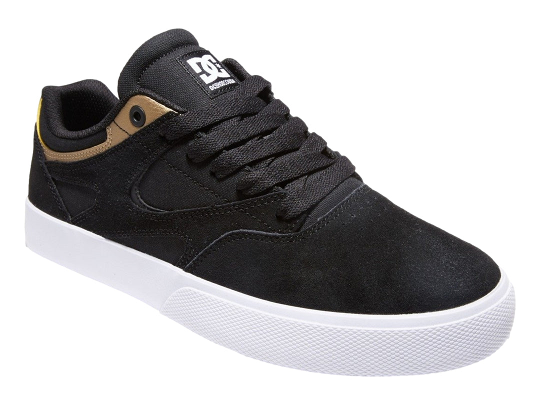 Tenis DC Shoes modelo Kalis Vulc en color negro con detalles dorados y suela blanca.