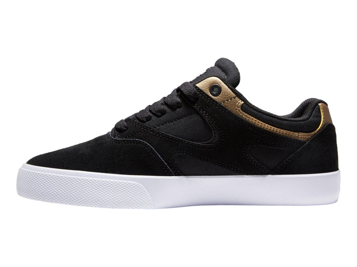 Tenis DC Shoes modelo Kalis Vulc en color negro con detalles dorados y suela blanca.