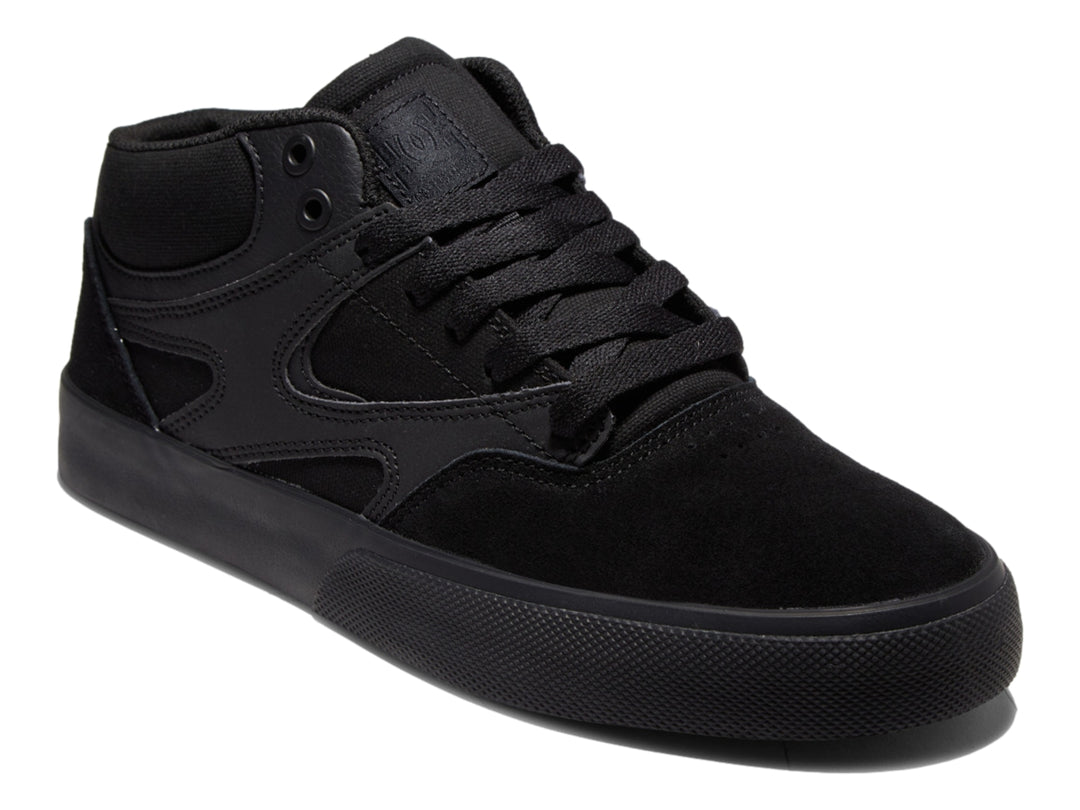 Tenis DC Shoes Kalis Vulc Mid en color negro total, diseño de corte medio y suela vulcanizada.