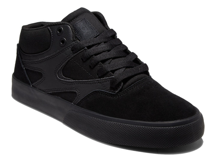 Tenis DC Shoes Kalis Vulc Mid en color negro total, diseño de corte medio y suela vulcanizada.