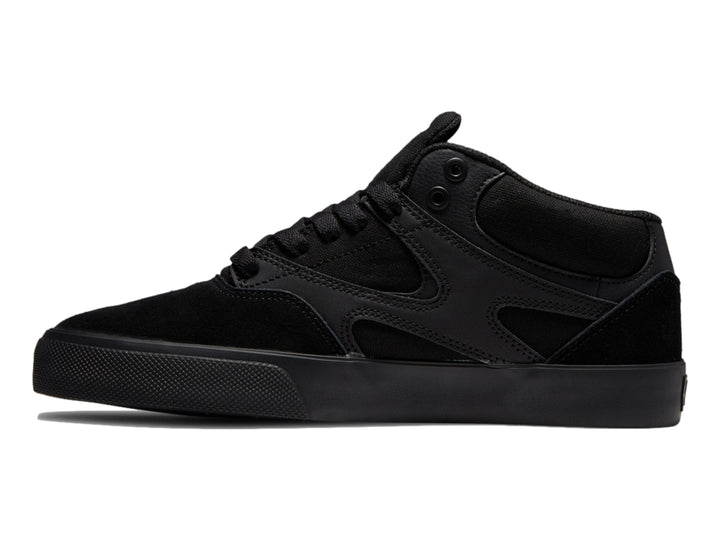 Tenis DC Shoes Kalis Vulc Mid en color negro total, diseño de corte medio y suela vulcanizada.