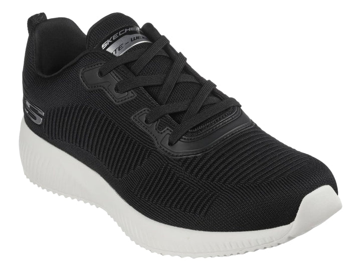 Tenis deportivos Skechers color negro con suela blanca y tejido acanalado.