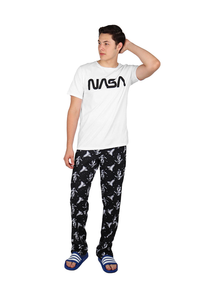 Hombre vistiendo pantalón largo negro con estampado blanco y camiseta blanca.