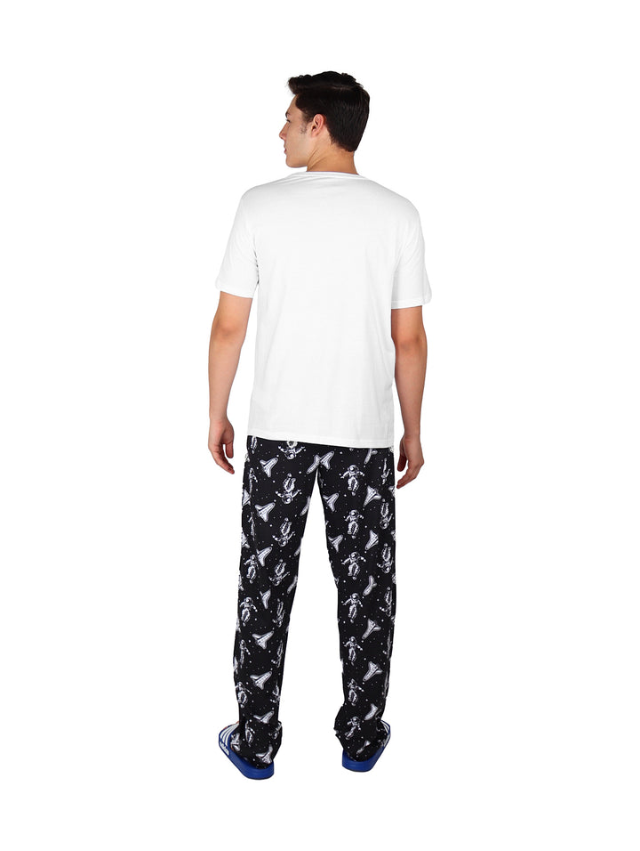 Hombre vistiendo pantalón largo negro con estampado blanco y camiseta blanca.