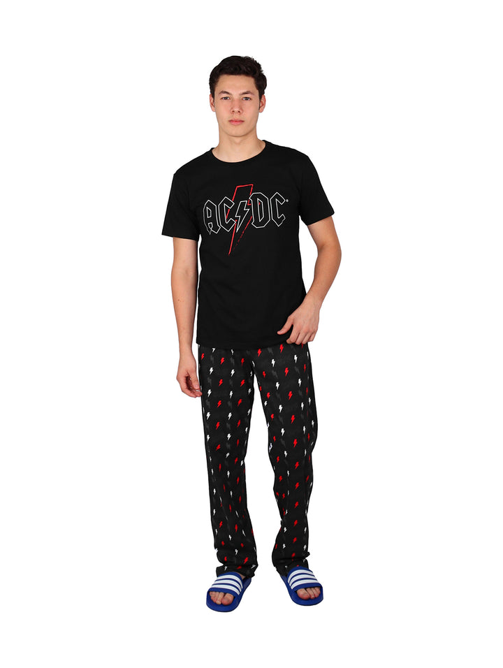 Hombre vistiendo pijama de pantalón largo negro con estampado de rayos rojos y camiseta negra.